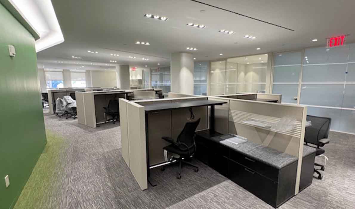 NYC office buildout with modern workstations and green accent wall by Universal Management, commercial construction company