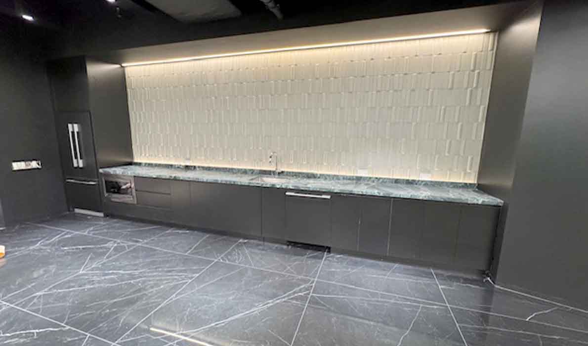 Modern breakroom at 370 7th Avenue renovated by Universal Contracting and Management, featuring black marble finishes, sleek cabinetry, and under-cabinet LED lighting.