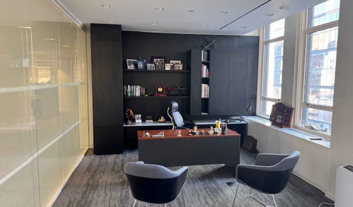 Executive office at 370 7th Avenue renovated by Universal Contracting and Management, featuring custom built-in shelving, large windows, and a modern professional design.